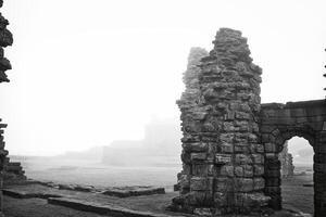 Ancient stone ruins in foggy landscape in Tynemouth Priory and Castle photo