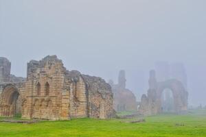 Ancient stone ruins in foggy landscape in Tynemouth Priory and Castle photo