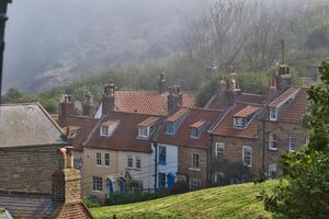 tradicional Inglés cabañas en un brumoso ladera en Robin capucha bahía, Yorkshire foto