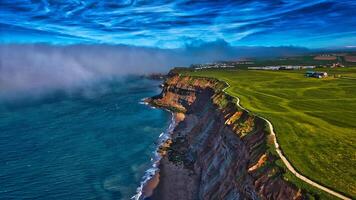 Aerial view of coastal cliff with green fields and misty ocean in Whitby, North Yorkshire photo