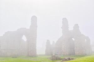 Ancient stone ruins in dense fog in Tynemouth Priory and Castle photo