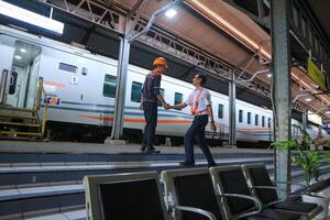 two Indonesian railway officers or KAI shake hands at the train station photo