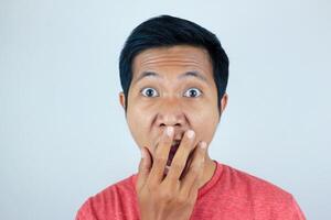 funny expression of shocked and surprised Asian man wearing a red t-shirt looking at the camera photo