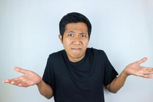 funny facial expression of asian man confused and spreading his arm, questioning the problem photo