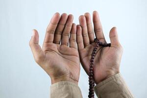 Male hand holding prayer beads rosary on white background. Ramadan kareem and ied mubarak concept. photo