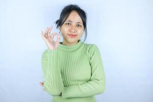 Smiling young Asian woman shows okay sign on white background. photo