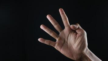 Male hand gesture number four closeup isolated on a black background photo