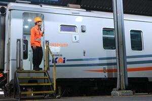 train officer stands in a train carriage at an Indonesian railway station photo