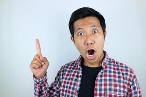 funny facial expression of asian man shocked and surprised while pointing at up side photo