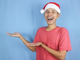 Handsome asian man in red christmas cap showing side and looking at camera. Christmas sale concept. photo