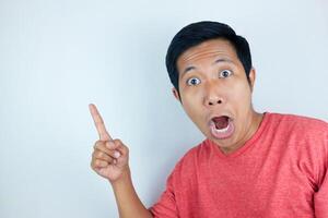 funny facial expression of asian man shocked and surprised while pointing at right side photo