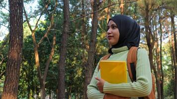 young muslim Woman holds book in her hands. Reading the book in the park during morning sun photo