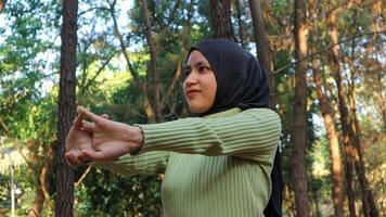 Muslim Women stretching arms and breathing fresh air in middle of pinewood forest while exercising photo