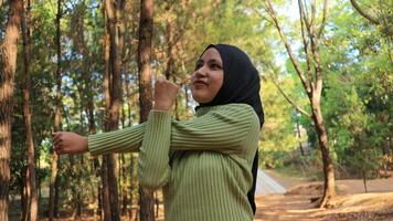 Muslim Women stretching arms and breathing fresh air in middle of pinewood forest while exercising photo