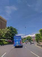 Trans jateng blue bus on the road with a view of the building in the morning, blue sky photo