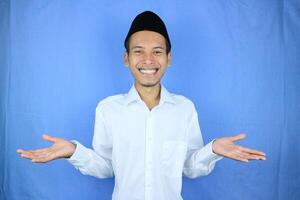 Smiling of excited muslim asian man wearing cap with open hand gesture photo