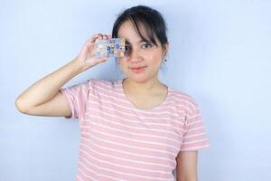 Smiling face expression of beautiful asian young woman showing credit card on white background photo