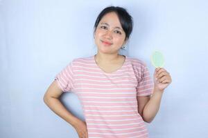 Smiling expression of young asian woman holding comb while looking at camera photo