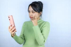 pensive expression of Asian woman holding smart phone on white background photo