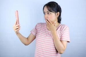 Shocked expression asian woman reading message on smart phone, on white background photo