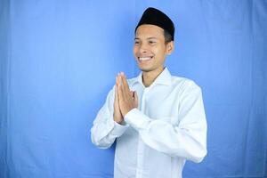 Smiling expression Asian Muslim man greeting Ramadan and Eid Al Fitr celebration on white background photo