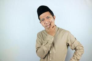 Confuse expression of asian muslim man doing thinking gesture, looking for idea on white background photo