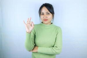 Smiling young Asian woman shows okay sign on white background. photo