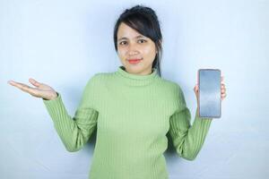 Young beautiful asian woman holding blank screen smart phone on white background photo