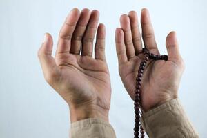 Male hand holding prayer beads rosary on white background. Ramadan kareem and ied mubarak concept. photo