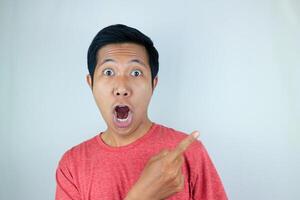 funny facial expression of asian man shocked and surprised while pointing at left side photo