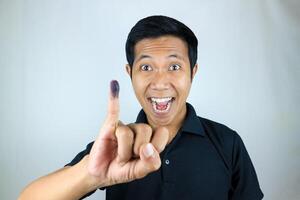 sonriente indonesio hombre demostración pequeño dedo después votación en de indonesia presidencial elección foto