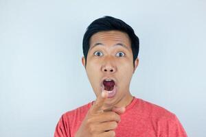 funny facial expression of asian man shocked and surprised while looking and pointing at the camera photo