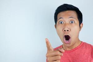 funny facial expression of asian man shocked and surprised while looking and pointing at the camera photo