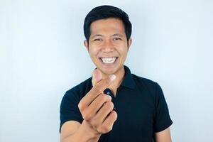 Young asian man isolated on white background smiling and gesturing a heart shape with hands photo