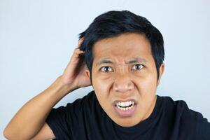 funny facial expression of asian man confused and scratching his head, questioning the problem photo
