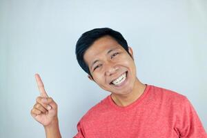 Asian man expression smiling while pointing to the side presenting the product. advertising concept photo