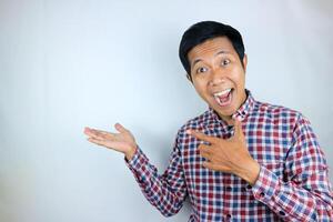 Asian man expression smiling while pointing to the side presenting the product. advertising concept photo
