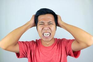 funny facial expression of stressed asian man holding his head, isolated on white background photo