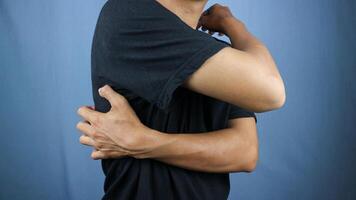 Asian young man scratching his back isolated blue background photo