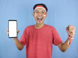 Excited expression young indonesian man celebrate indonesian independence day while holding phone. photo