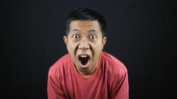 crazy amazed young man open mouth unbelievable information isolated on black background photo