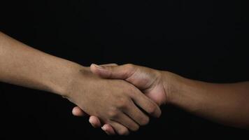 Close up two man shaking hand as agreement on black background. photo