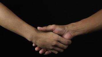 Close up two man shaking hand as agreement on black background. photo