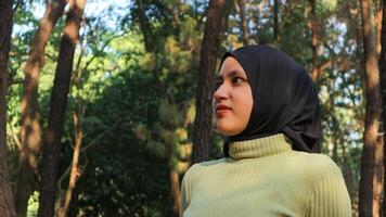 Close-up Muslim woman wearing head scarf in pine forest. Modern muslim woman, wearing black hijab. photo
