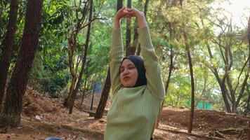 disfrutando el naturaleza. joven musulmán mujer brazos elevado disfrutando el Fresco aire en verano verde parque foto