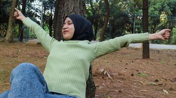 Enjoying the nature. Young muslim woman arms raised enjoying the fresh air in summer green park photo