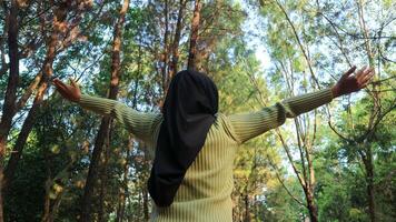 Enjoying the nature. Young muslim woman arms raised enjoying the fresh air in summer green park photo