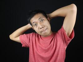 funny expression of asian man with hand on head isolated on black background photo