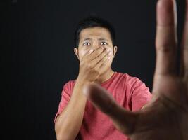 gesture Asian man covering his nose and making stop sign with his hand because of a strong smell. photo