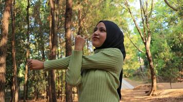 Muslim Women stretching arms and breathing fresh air in middle of pinewood forest while exercising photo